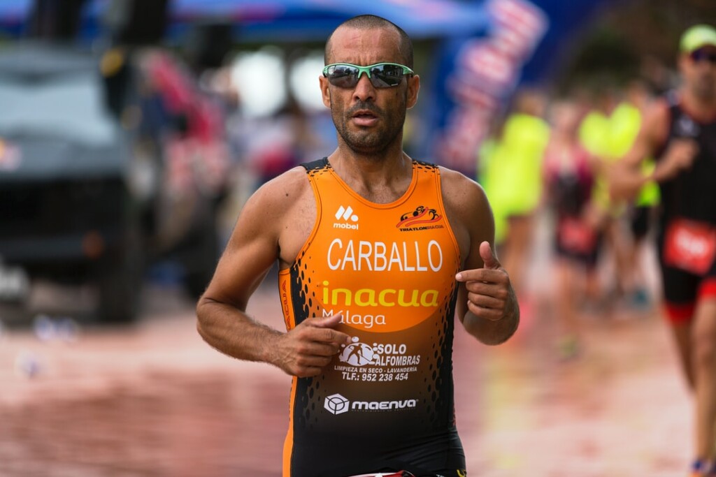A man in an orange running attire wearing sports sunglasses