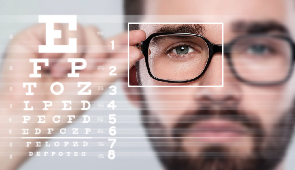 A man holding the side of his eyeglasses and trying to read the letters