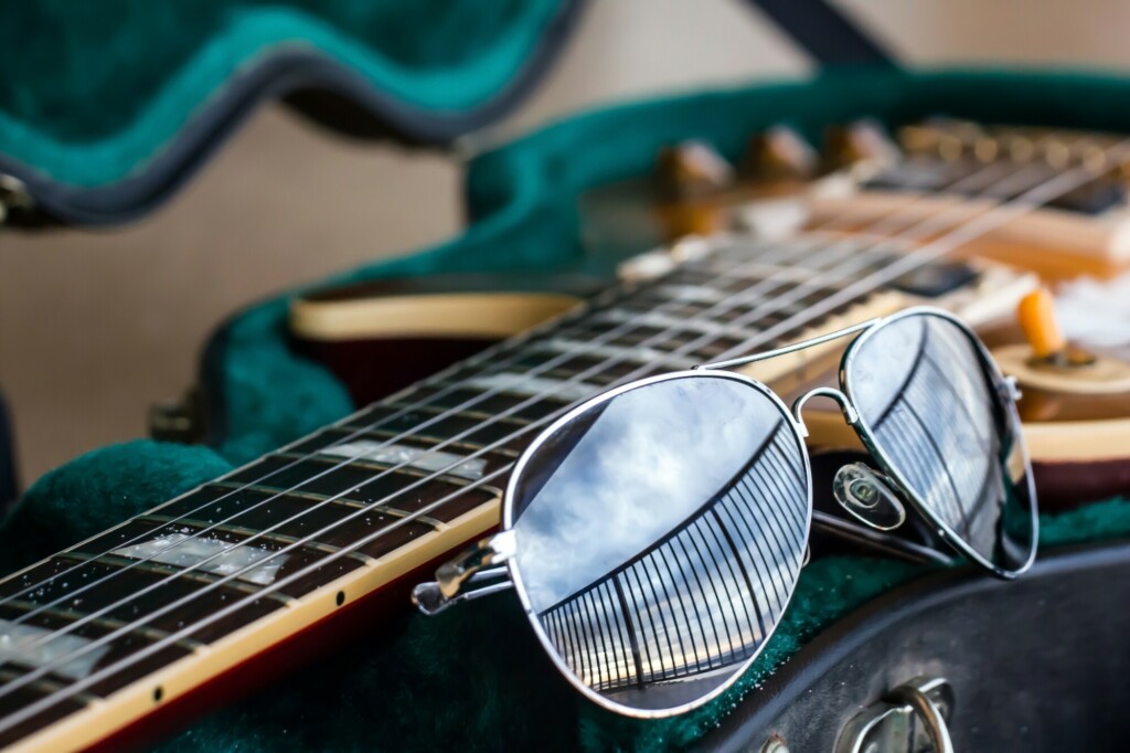 Designer sunglasses beside a guitar