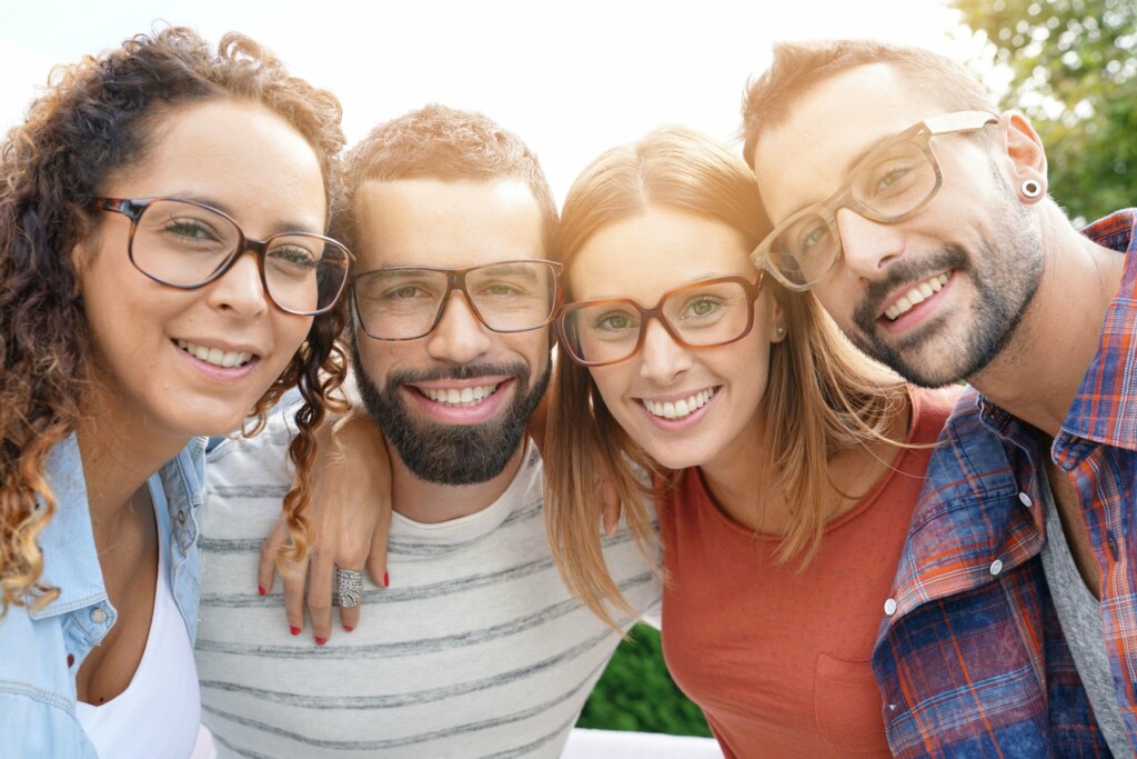 4 smiling people wearing eyeglasses huddled together