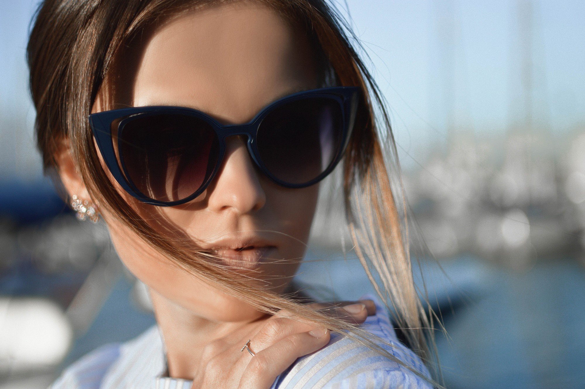 A woman facing sideways wearing designer sunglasses
