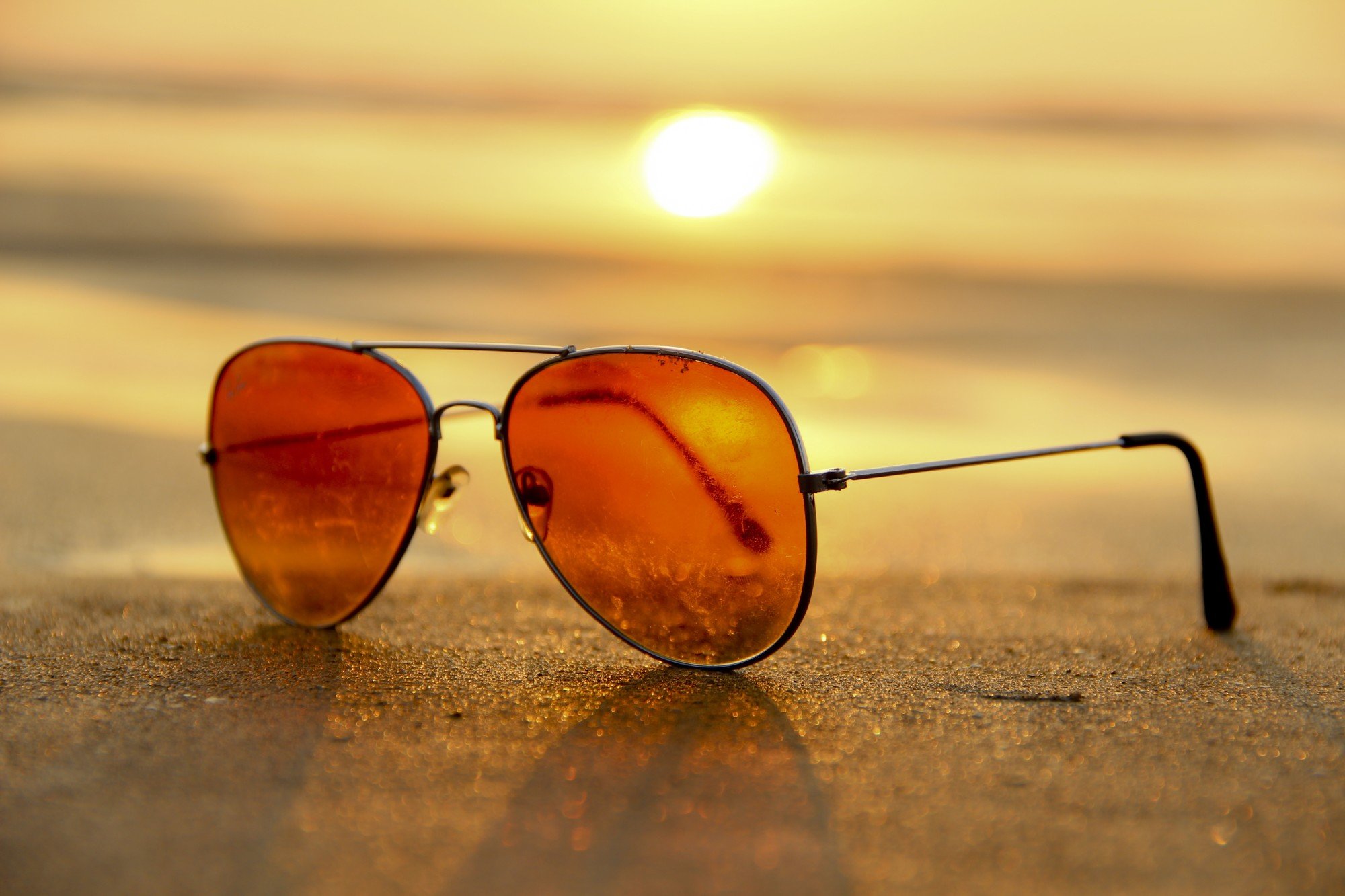Sunglasses displayed on the top of a cemented top with the sunset on the background