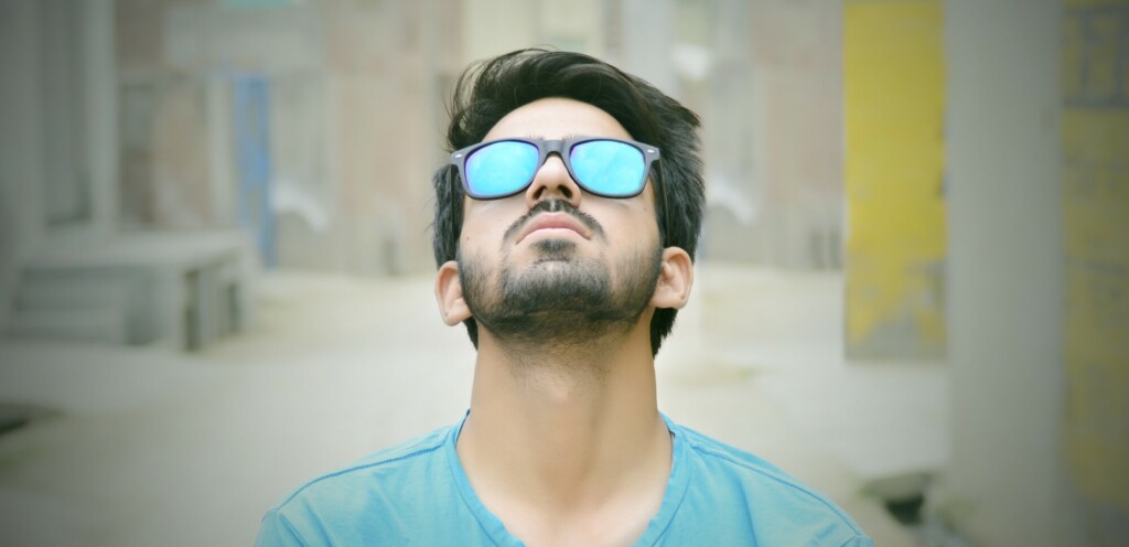 A man looking up on the sky wearing designer sunglasses