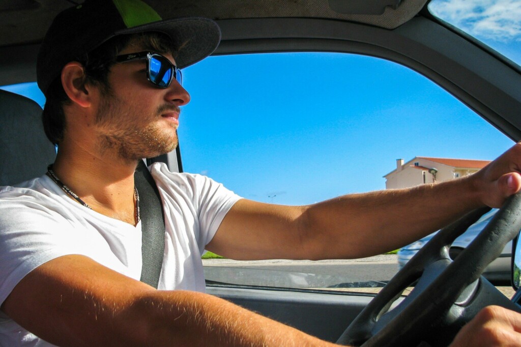 A man driving his car while wearing sunglasses