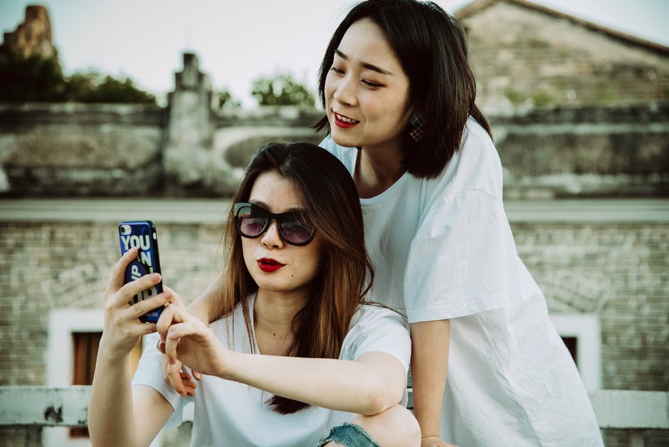 Two women taking a selfie with the woman at the front part wearing designer sunglasses