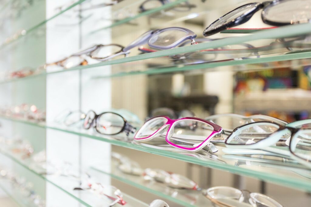 variety of eyeglasses on a glass shelf
